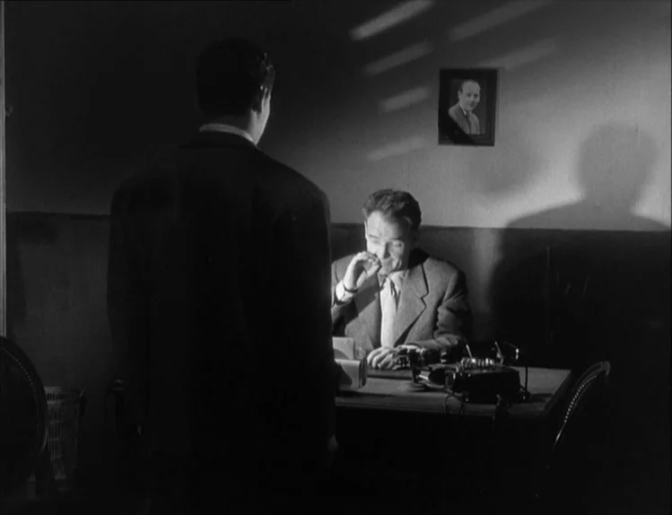 Bob le Flambeur (1956) movie still: medium — A spartan office space features a desk and a framed photograph on the wall. Two men interact in a…