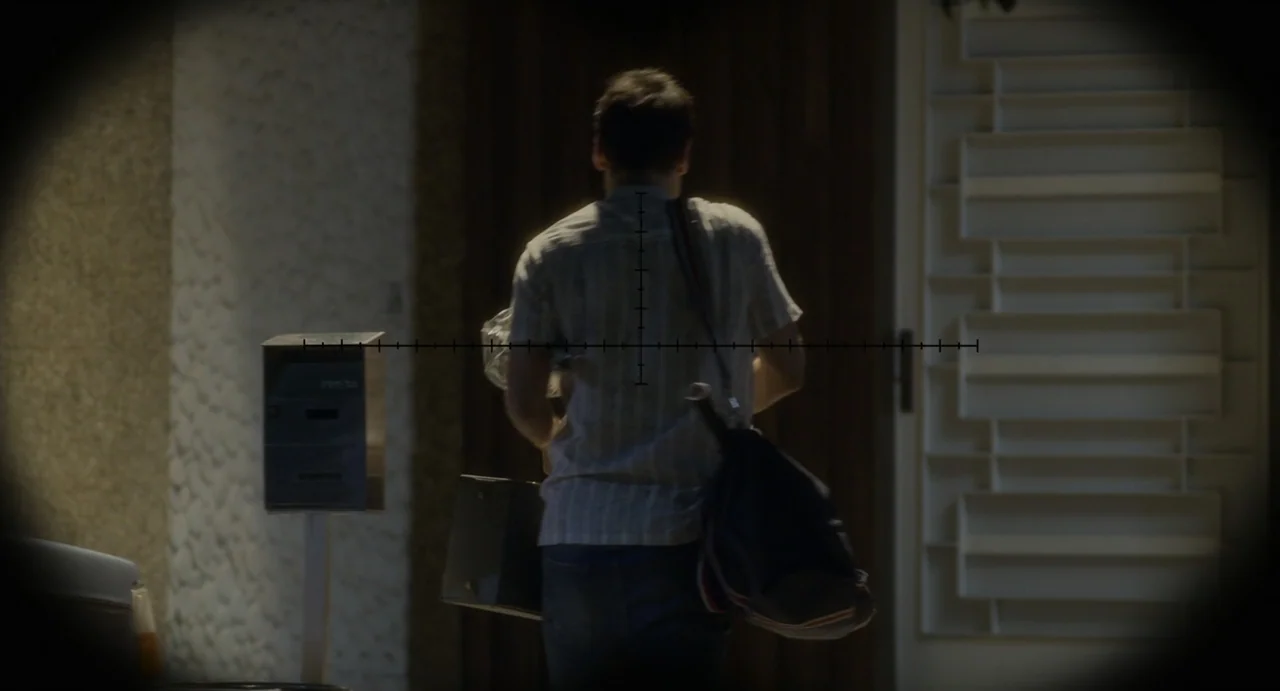 Little White Lies (2010) movie still: medium — A dark exterior walkway with a metal mailbox and a white door in background. A man carrying a bag and…