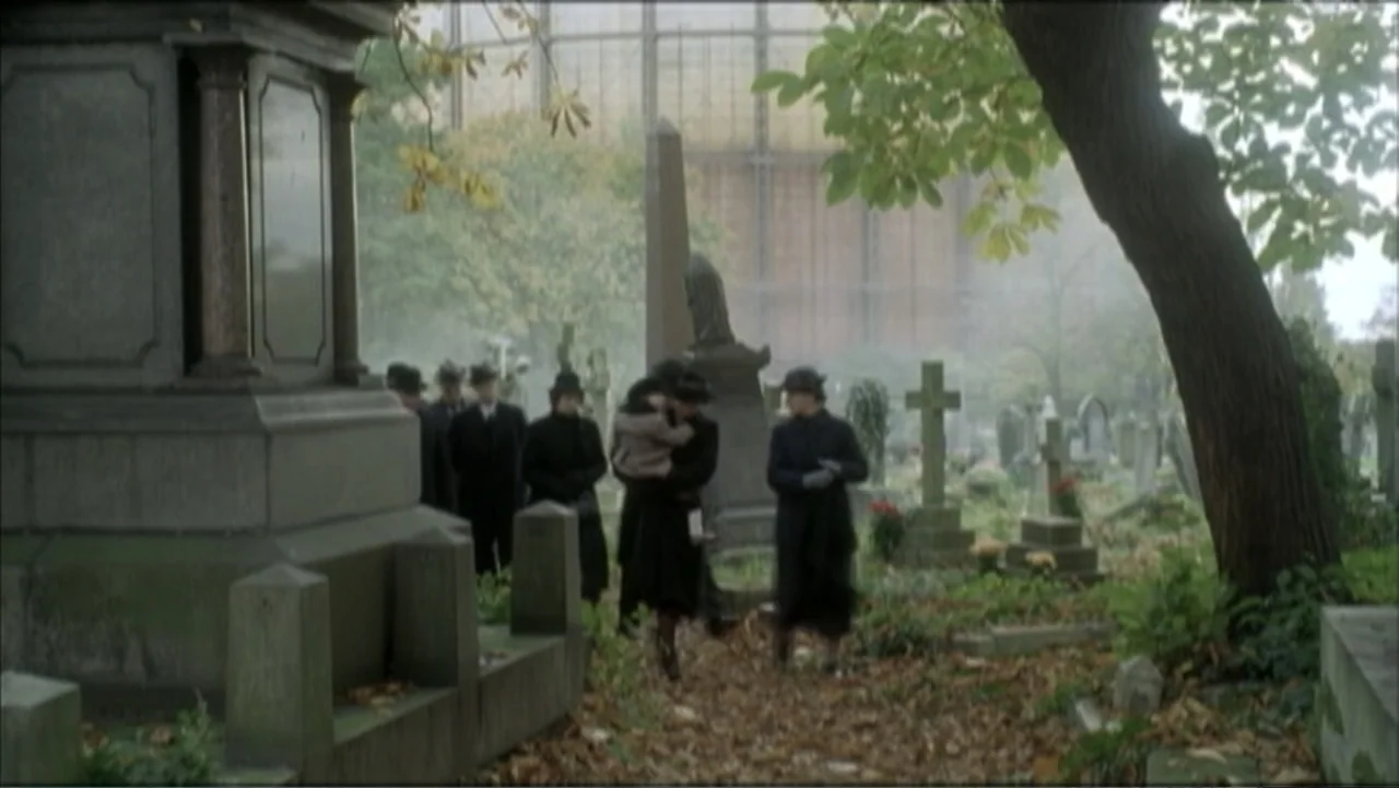 The Gathering Storm (2002) movie still: wide — A sprawling historic graveyard features stone monuments and overgrown trees in a foggy setting. A…