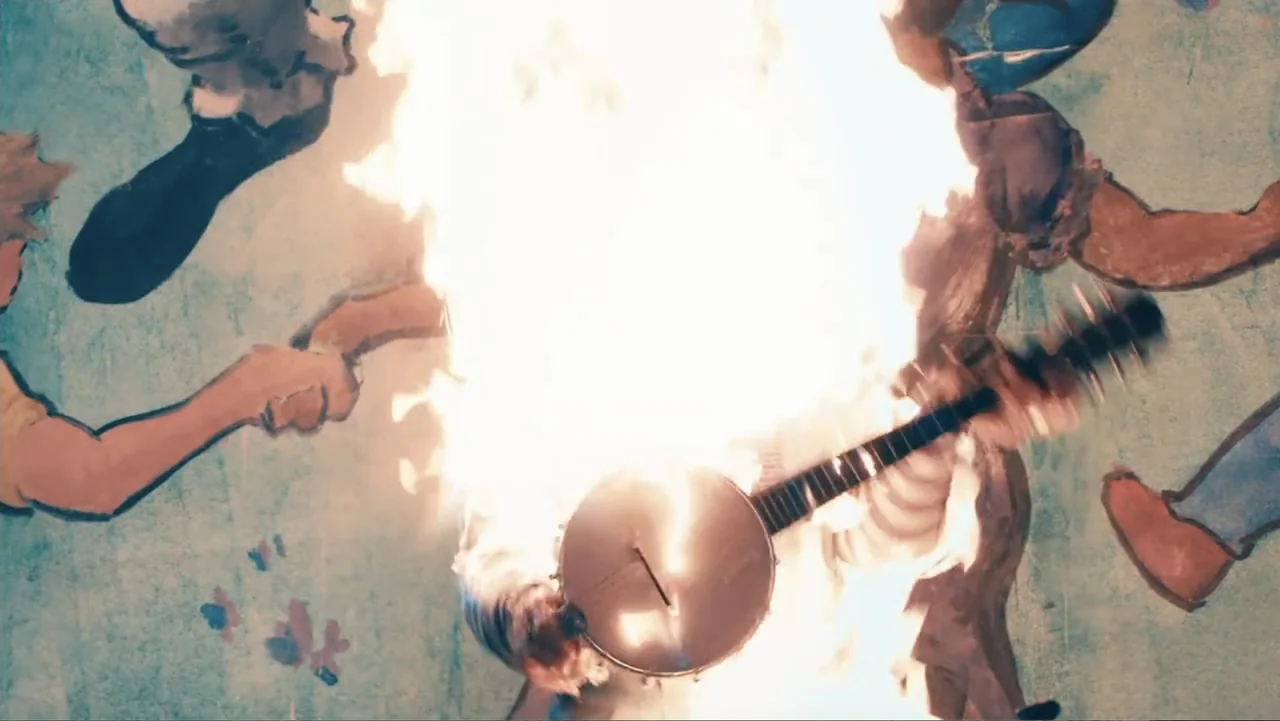 Terrifier 2 (2022) movie still: medium — A large mural of figures holding hands is painted on a light blue wall. A bright explosion of fire erupts…