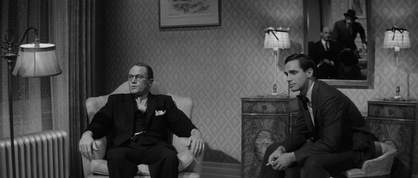 Compulsion (1959) movie still: medium — An interior hotel room features damask-patterned wallpaper, two armchairs, and matching table lamps. Two men…