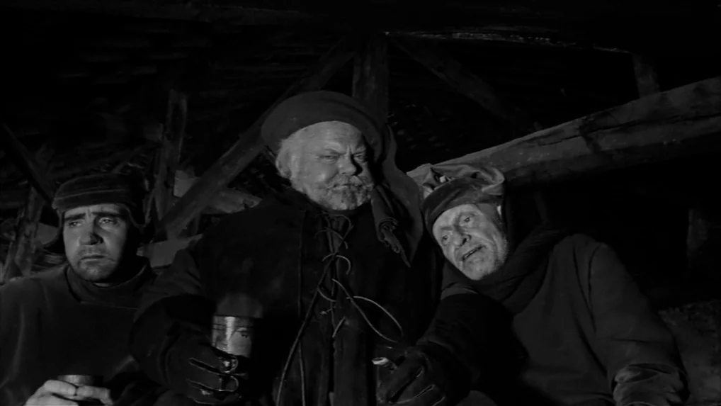 Falstaff (Chimes at Midnight) (1965) movie still: medium — A dark, cramped attic space features wooden roof rafters and exposed timber beams. Three…