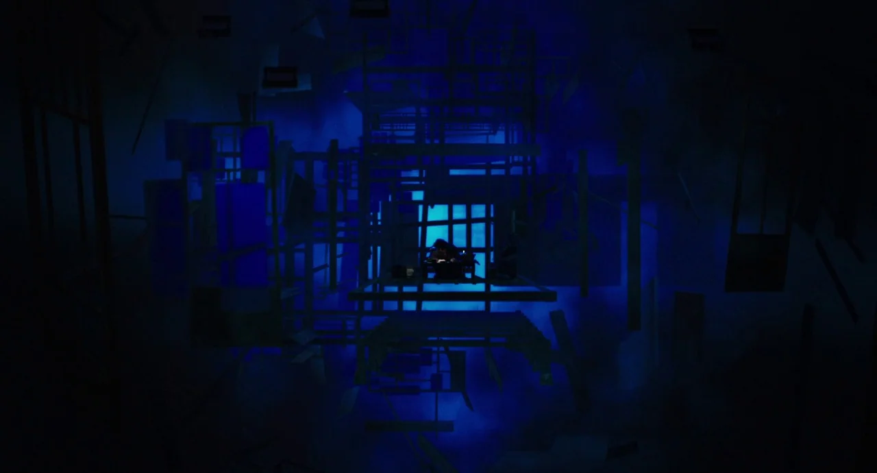 No Longer Human (2019) movie still: wide — A dark, abstract void filled with floating wooden frames and geometric structures. A single person sits…