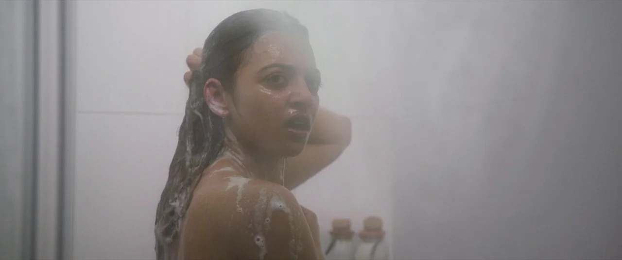 The Wedding Guest (2018) movie still: closeup — A steam-filled bathroom with tiled walls partially obscured by a dense layer of fog. A woman with…