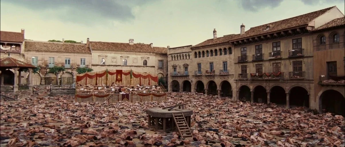 Perfume: The Story of a Murderer (2006) movie still: establishing — A stone-paved medieval town square is densely covered with hundreds of prone…