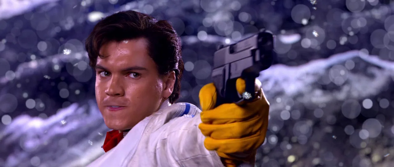 Speed Racer (2008) movie still: closeup — A man stands outdoors against a blurry backdrop of dark night snow. He points a black handgun directly…