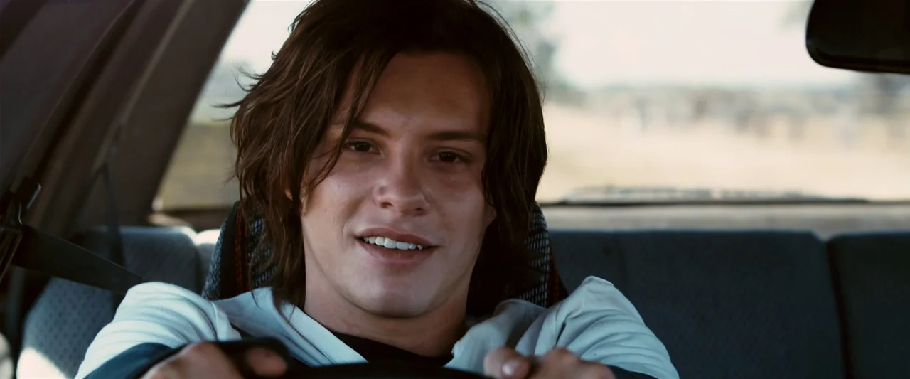 The Loved Ones (2009) movie still: closeup — The interior of a moving vehicle with patterned headrests and seatbelts visible. A young man sits in…