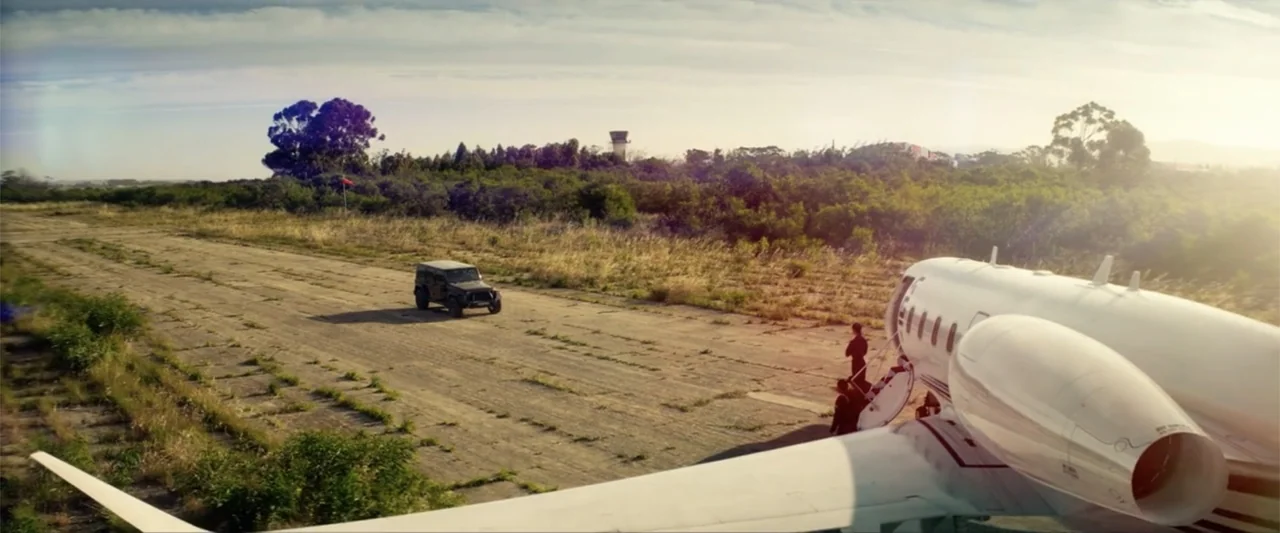 Bloodshot (2020) movie still: wide — A private jet stands on a desolate, overgrown concrete airstrip at golden hour. A dark SUV is parked nearby…