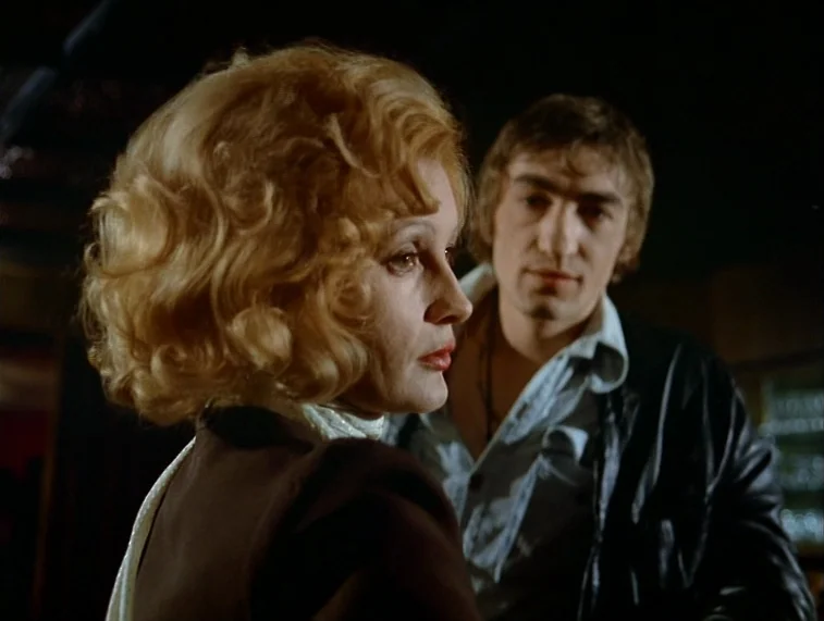 Mother Kusters Goes To Heaven (1975) movie still: medium — A dimly lit bar setting with a dark backdrop and indistinct interior architecture. A…