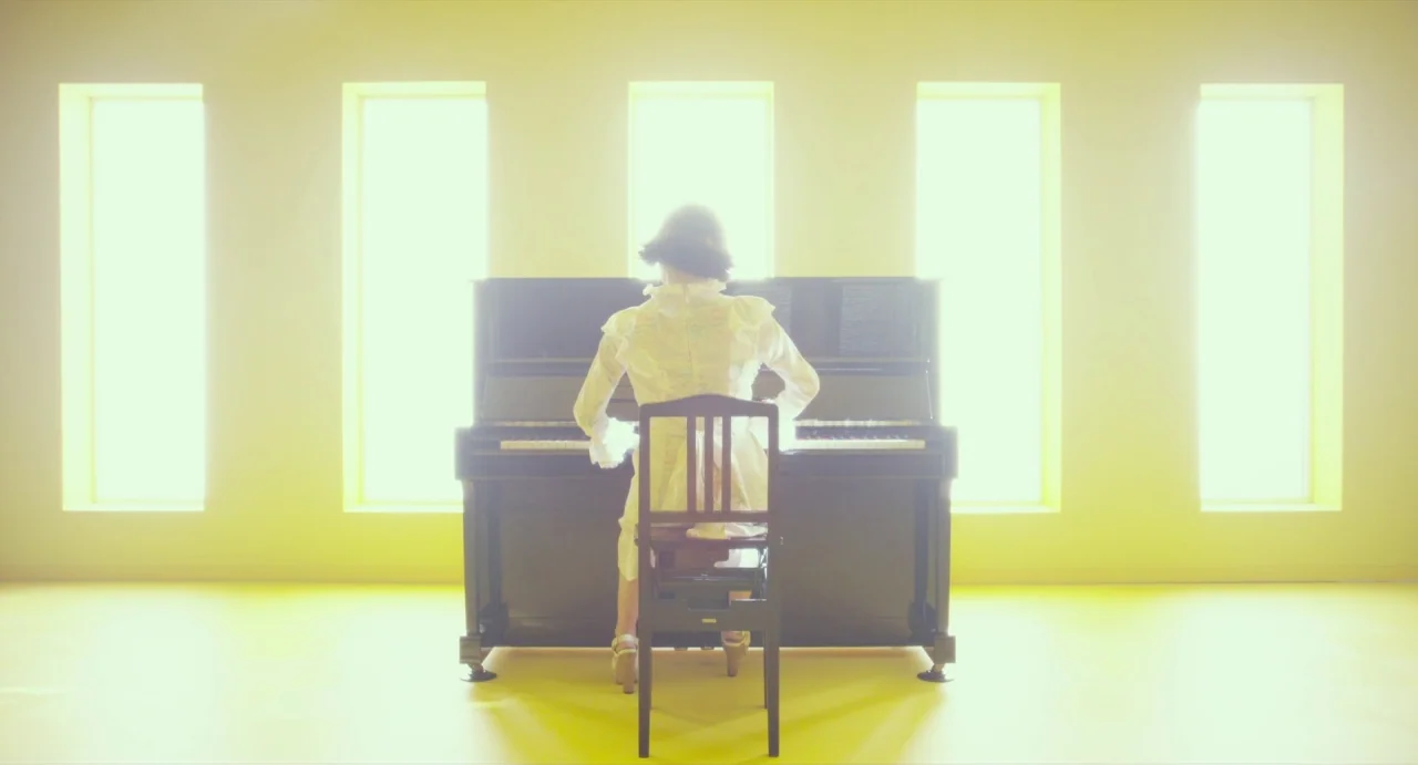 Making of: Antiporno (2016) movie still: fullbody — A minimalist room has vibrant yellow walls and floor with five evenly spaced windows. A woman in…