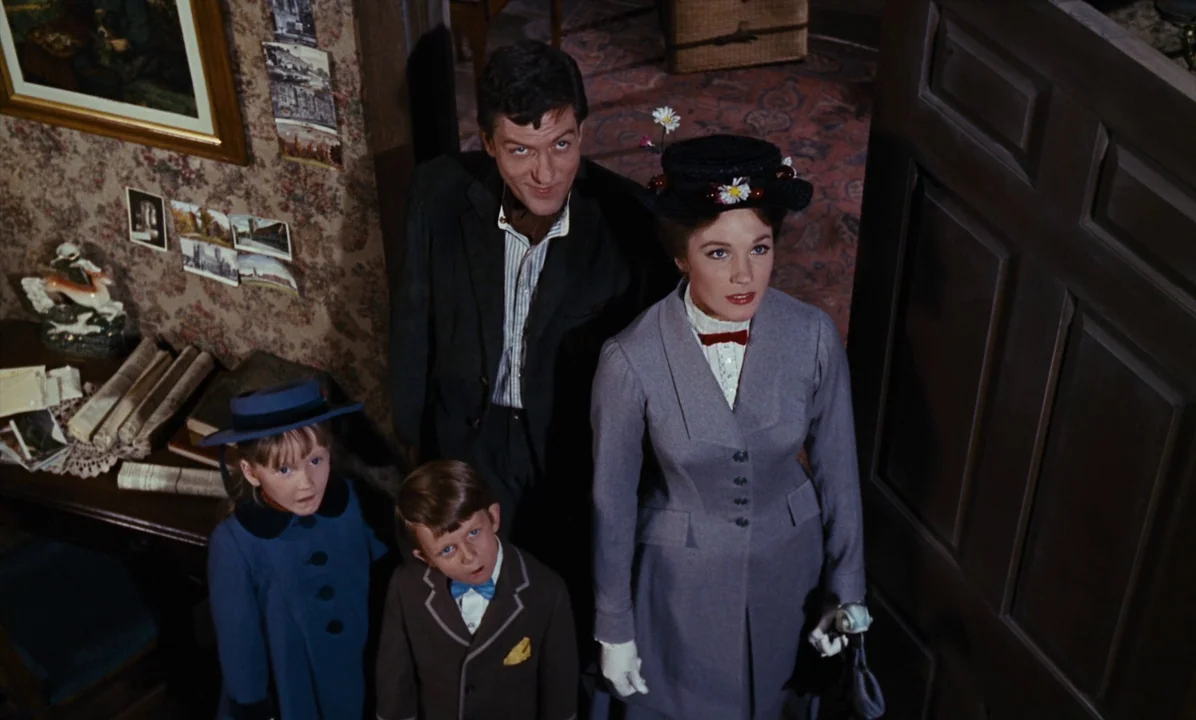 Mary Poppins (1964) movie still: medium — An interior hallway features wallpapered walls adorned with small framed photographs and postcards. A…