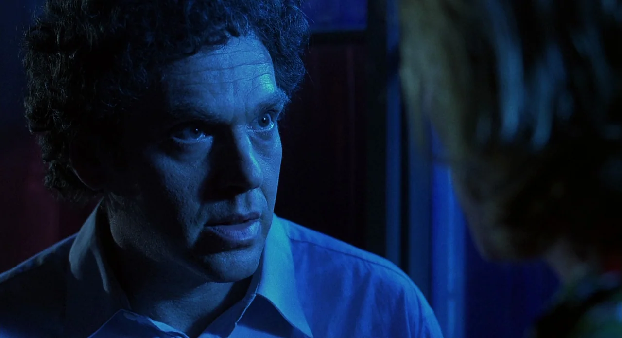 Tales from the Crypt: Demon Knight (1995) movie still: closeup — A dark interior of a car at night with blue light flooding the cabin. A middle-aged…