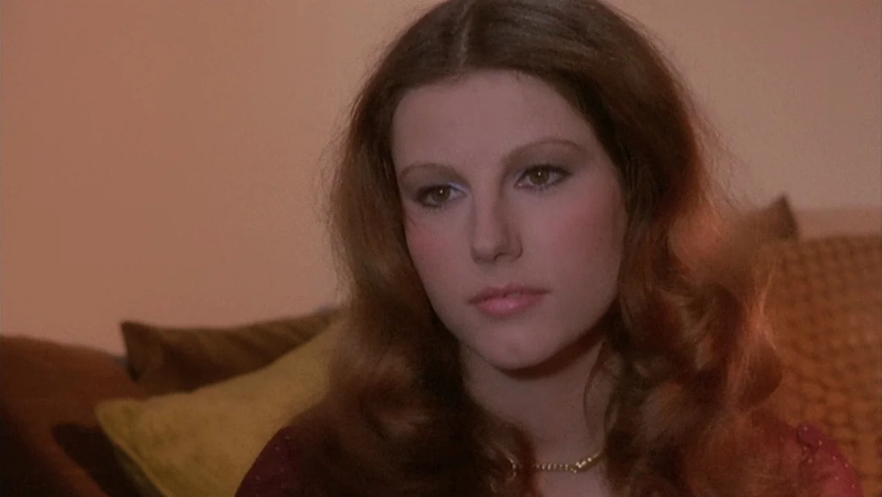 The Black Belly of the Tarantula (1971) movie still: closeup — A residential interior space features soft-focus pillows visible in the blurred…