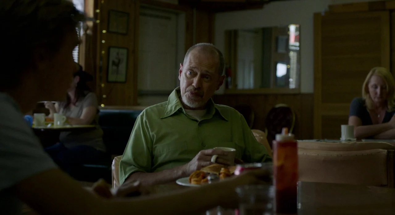 Lean on Pete (2017) movie still: medium — A dimly lit diner with wooden paneling and booths featuring patrons at multiple tables. An older man sits…