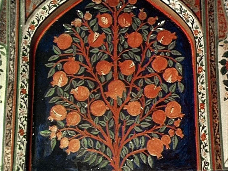 Ashik Kerib (1988) movie still: closeup — A decorative arched wall alcove contains a detailed mural of a pomegranate tree. The painting uses…