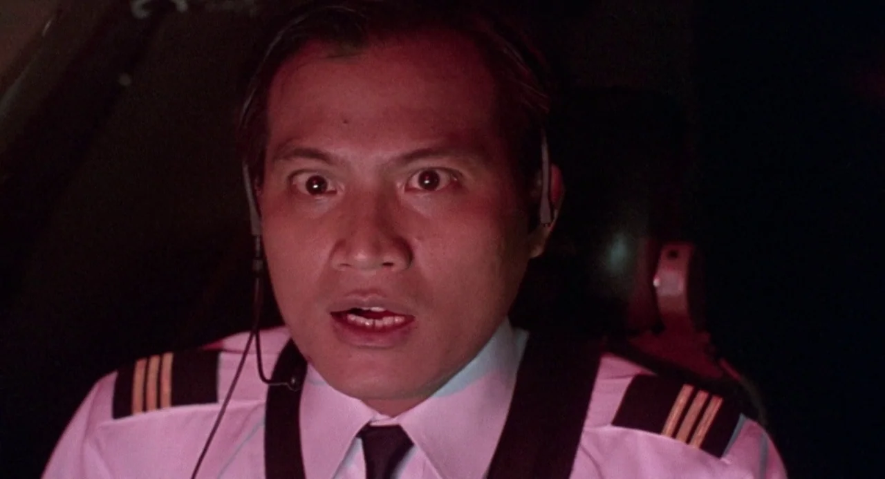 Godzilla vs. Destoroyah (1995) movie still: closeup — The interior of a darkened airplane cockpit lit in deep red light. A male pilot in uniform…
