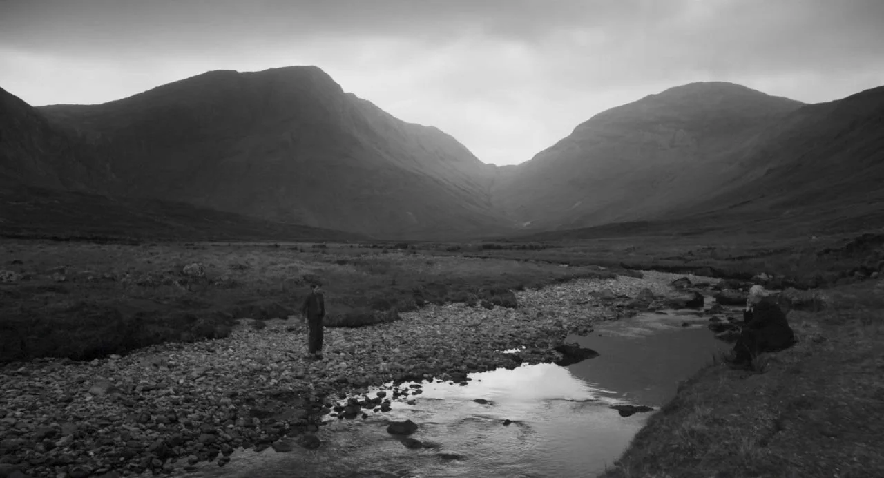 Song of Granite (2017) movie still: wide — A vast, mountainous valley landscape features a rocky stream winding through the center. A small child…