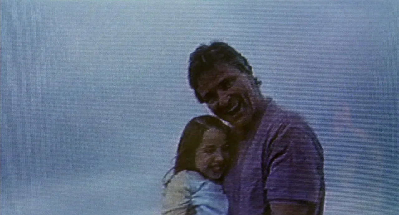 The Nameless (1999) movie still: medium — A man and a child stand together against a bright, hazy, overcast background. They embrace closely while…