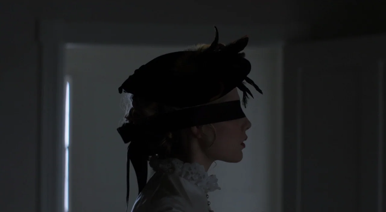 I Am The Pretty Thing That Lives In The House (2016) movie still: closeup — A dimly lit room with an out-of-focus doorway in the background. A woman…