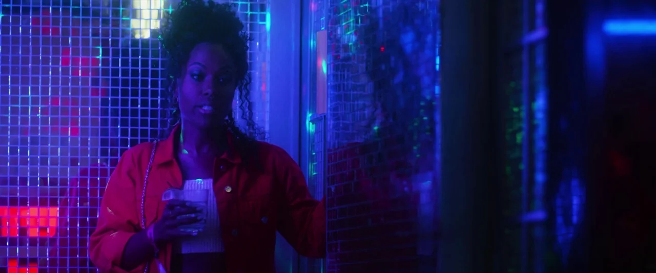 Someone Great (2019) movie still: medium — A dark environment featuring walls covered in reflective square tiles illuminated by neon lights. A woman…