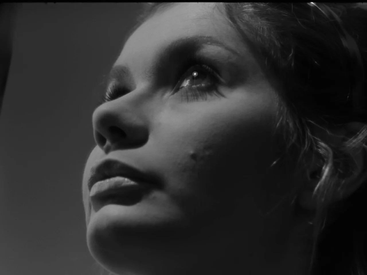 The Baby Carriage (1963) movie still: closeup — A close-up of a woman's face shown in high-contrast black and white. She tilts her head back to look…
