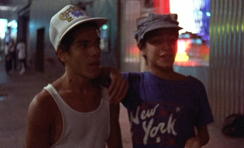 Paris Is Burning (1990) movie still: medium — Two teenage boys walk down a dimly lit urban exterior at night. One has his arm around the other while…