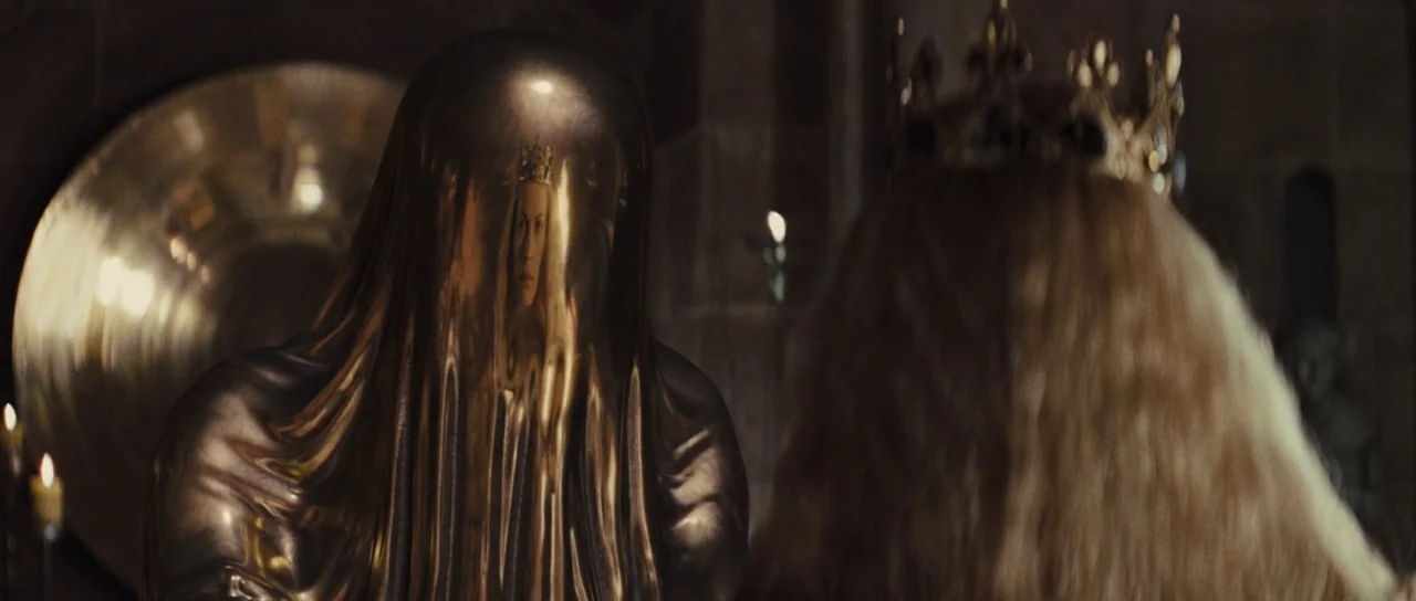 Snow White and The Huntsman (2012) movie still: medium — A stone interior space contains a tall, smooth metallic statue. A queen with long blonde…