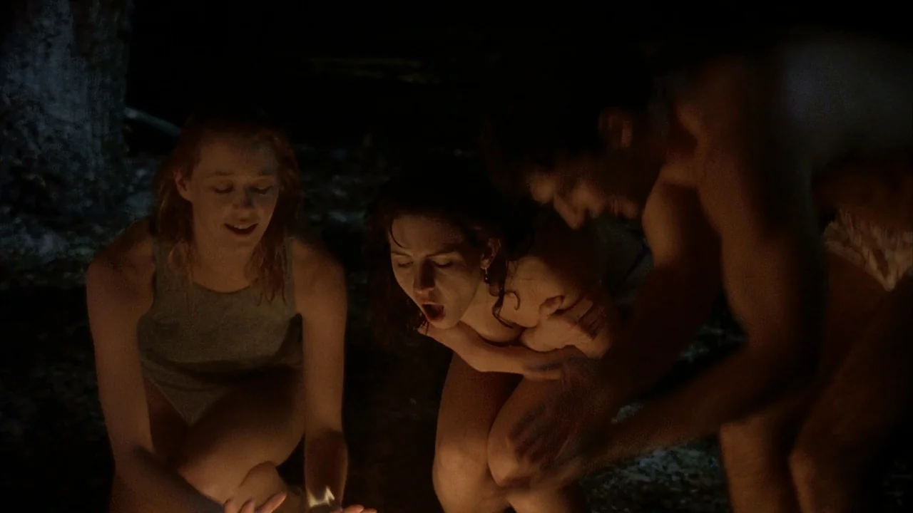 Jason Goes To Hell (1993) movie still: medium — Three young people crouch closely around a small fire in a dark, outdoor setting. They lean toward…