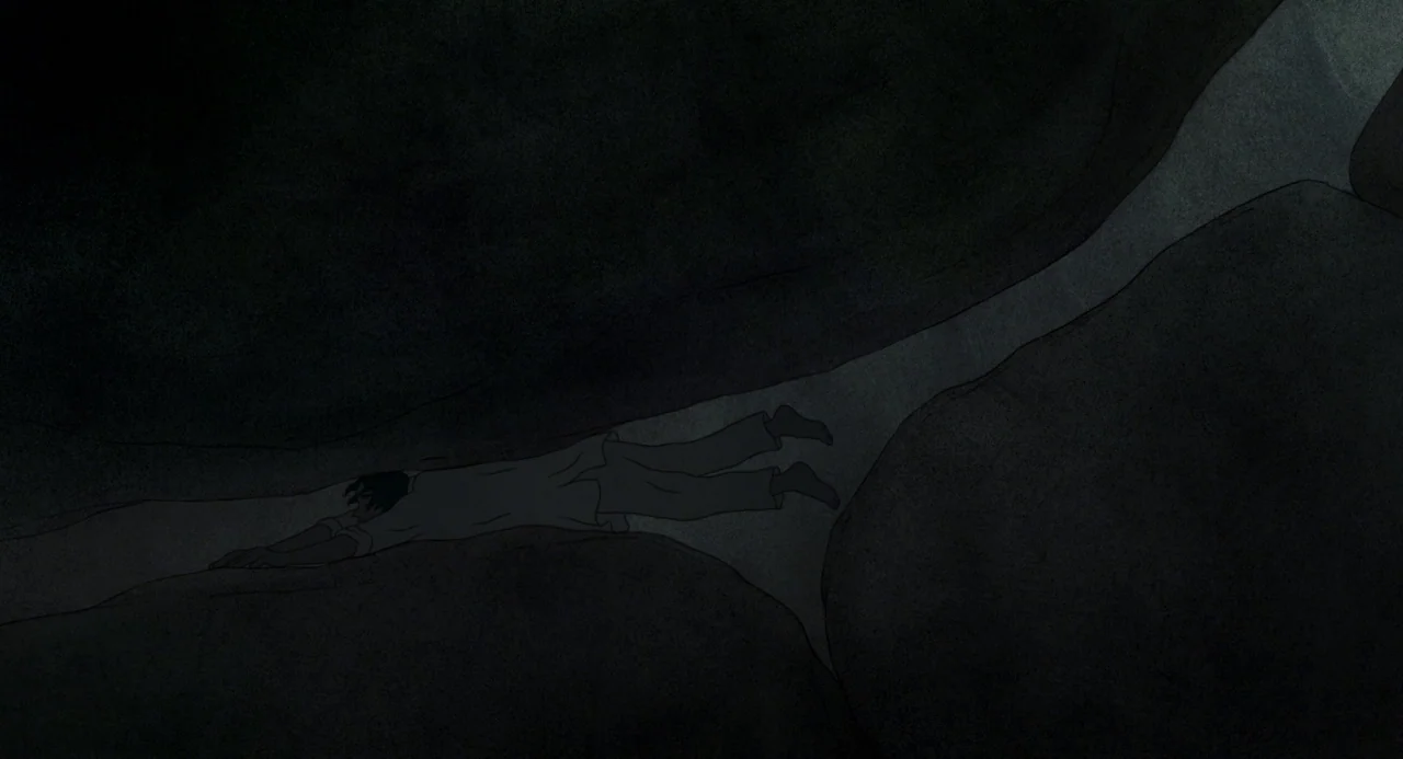 The Red Turtle (2016) movie still: wide — A dark narrow subterranean passage formed by large uneven rock formations. A person crawls on their…
