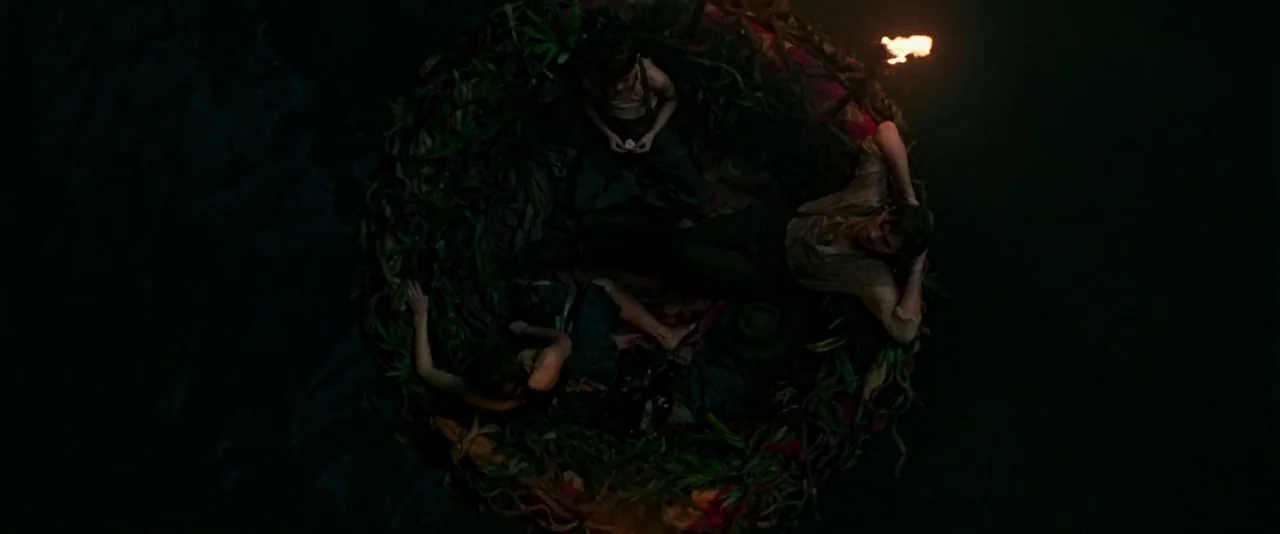 Pan (2015) movie still: wide — A circular raft made of woven vegetation floats on dark, still water at night. Three people are positioned within the…