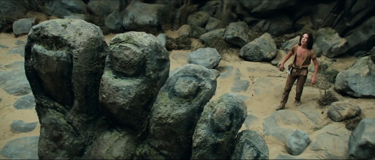 The NeverEnding Story (1984) movie still: wide — A desolate, sandy expanse is littered with large grey boulders and carved stone fragments. A young…