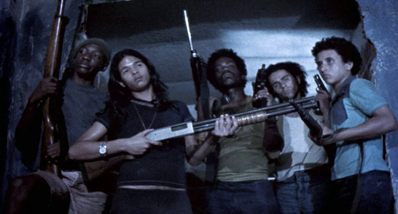 City of God (2002) movie still: medium — A dimly lit concrete stairwell with rough walls and a low ceiling. A group of five young men stand huddled…