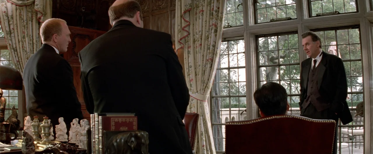 Rush Hour (1998) movie still: medium — A wood-paneled study features large windows with floral curtains and ornate decorative figures. Three men in…