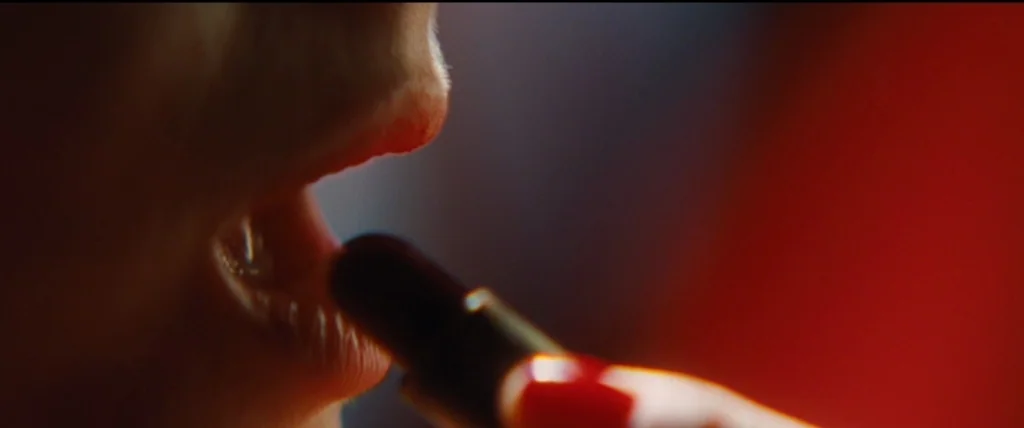 Inglourious Basterds (2009) movie still: closeup — An extreme close-up of human lips being painted with a dark lipstick tube. A single finger with…