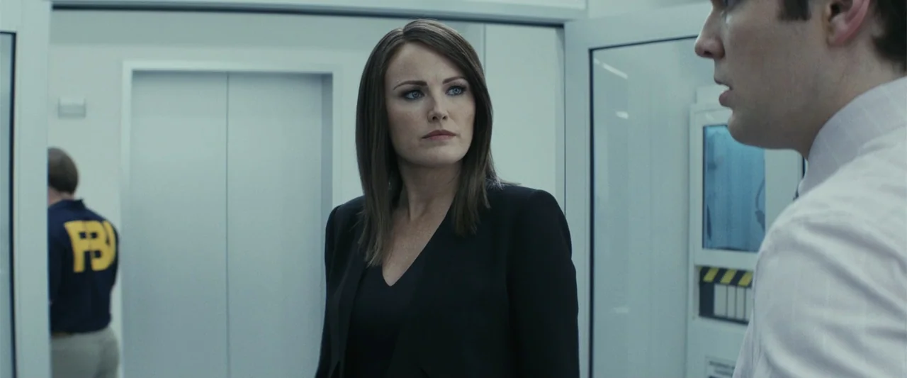 Rampage (2018) movie still: medium — A modern, brightly lit office environment features white walls and glass door partitions. A woman in a dark…