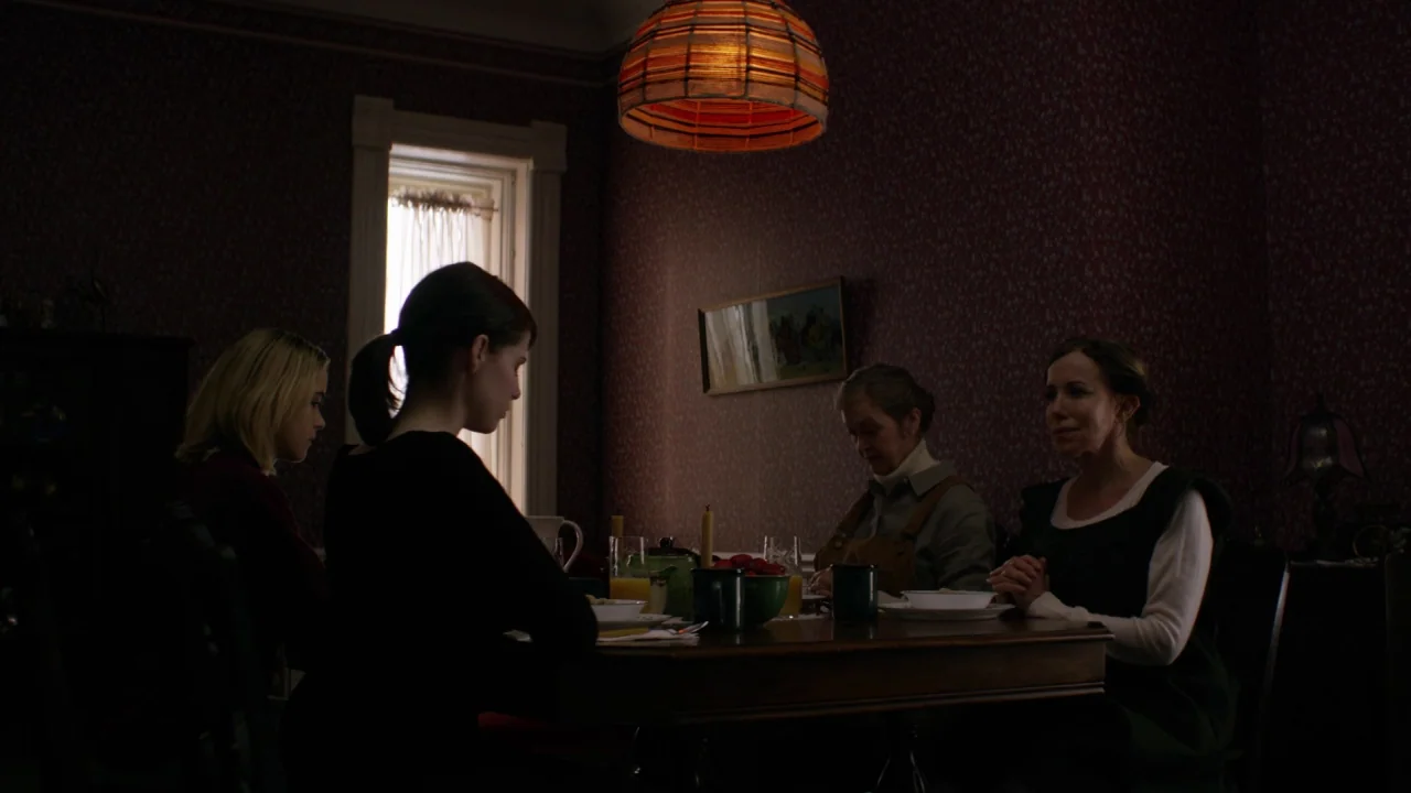 The Blackcoat’s Daughter (2015) movie still: wide — A dining room features floral wallpaper and an orange patterned lampshade hanging above the…