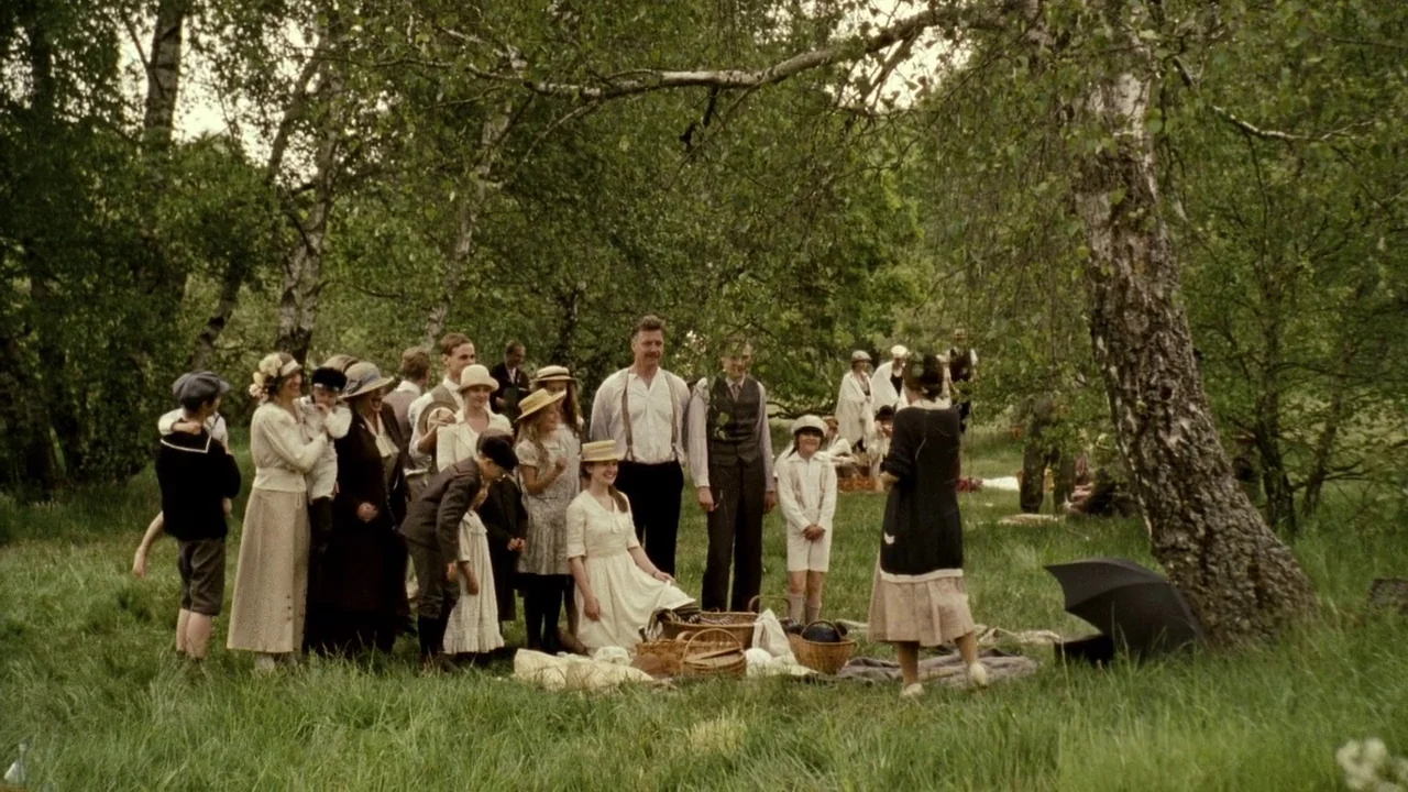 Everlasting Moments (2008) movie still: wide — A group of people dressed in early twentieth-century clothing gather in a grassy meadow. They stand…
