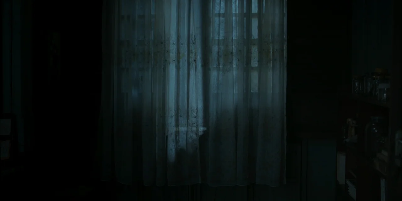 Nokturno (2024) movie still: establishing — A dark interior room features a window covered by a sheer patterned curtain. Faint moonlight penetrates…
