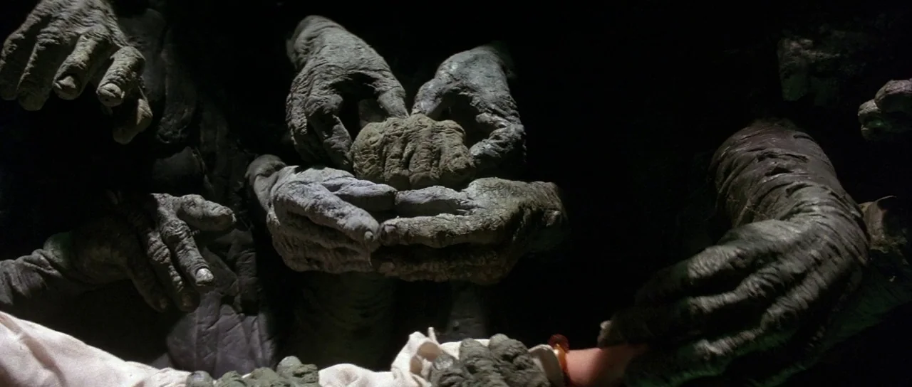 Labyrinth (1986) movie still: closeup — A dark, formless void is filled with several massive, weathered, and leathery-skinned creature hands. The…
