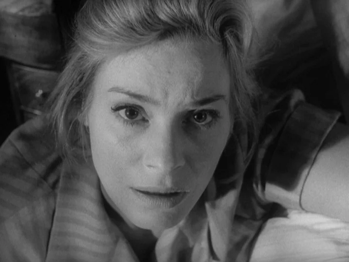 The Silence (1963) movie still: closeup — A woman lies on a surface looking directly up toward the lens in a room. She rests her arm against a white…