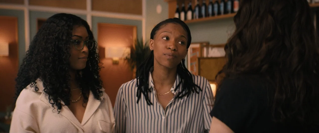 Something from Tiffany's (2022) movie still: medium — A dimly lit indoor space with teal walls and shelves holding wine bottles. Three women are…