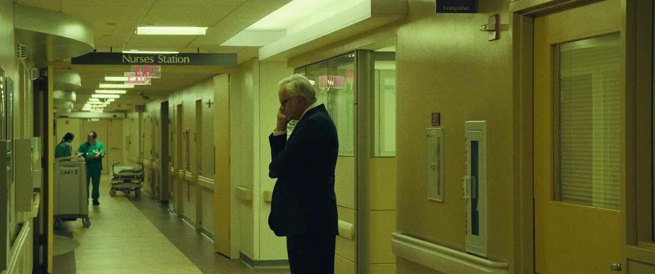 Dark Waters (2019) movie still: wide — A long, institutional hallway features pale yellow walls and recessed fluorescent lighting fixtures above. A…