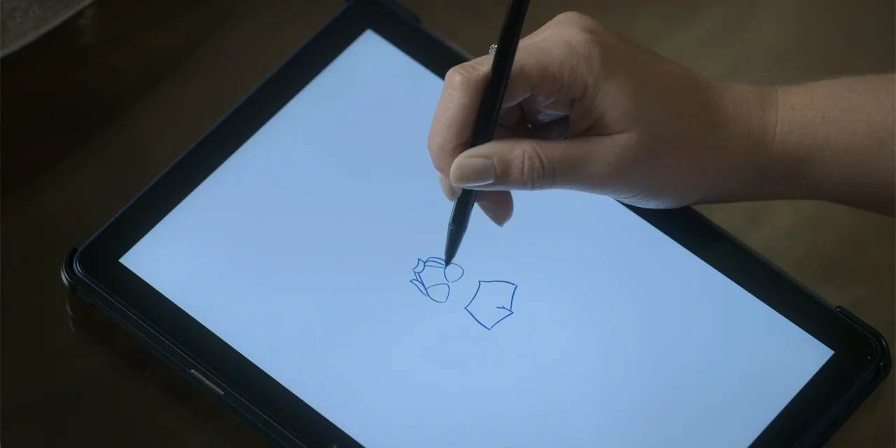 An Unforgettable Year - Summer (2023) movie still: closeup — A close view shows a hand using a digital stylus on a tablet screen. The hand draws a…