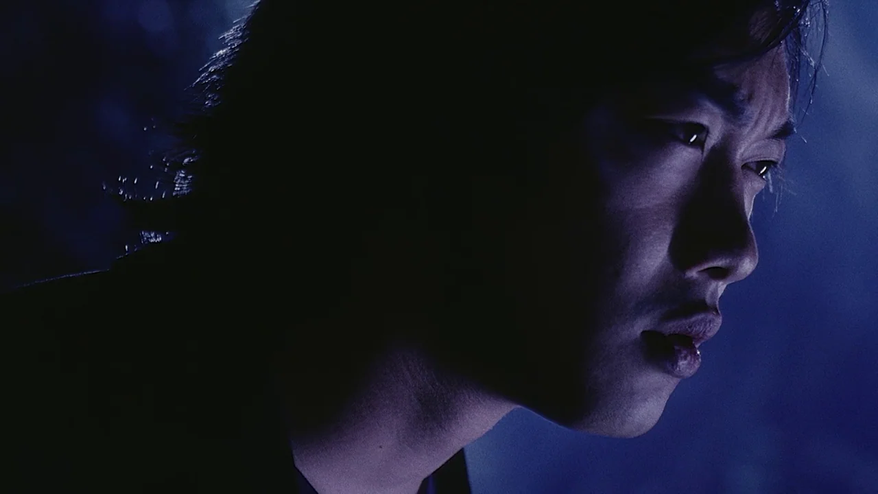 Visible Secret (2001) movie still: closeup — A man stands in an dark outdoor space at night with cool lighting. He looks toward the side while…