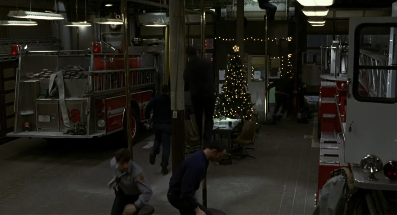 Ladder 49 (2004) movie still: wide — A spacious fire station bay contains large red trucks and a decorated Christmas tree. Multiple firefighters…