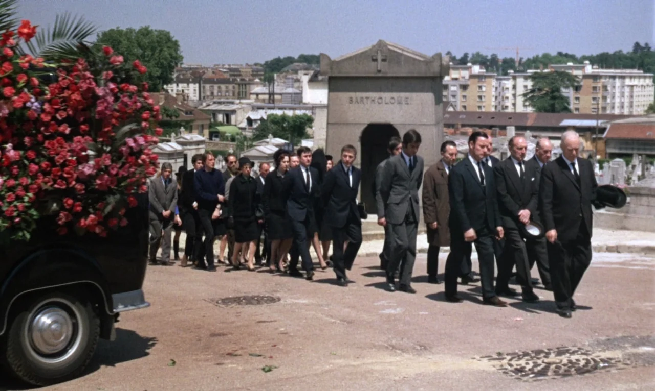 The Bride Wore Black (1968) movie still: wide — A group of people in formal black suits walks through a sunlit cemetery. They move past a large…