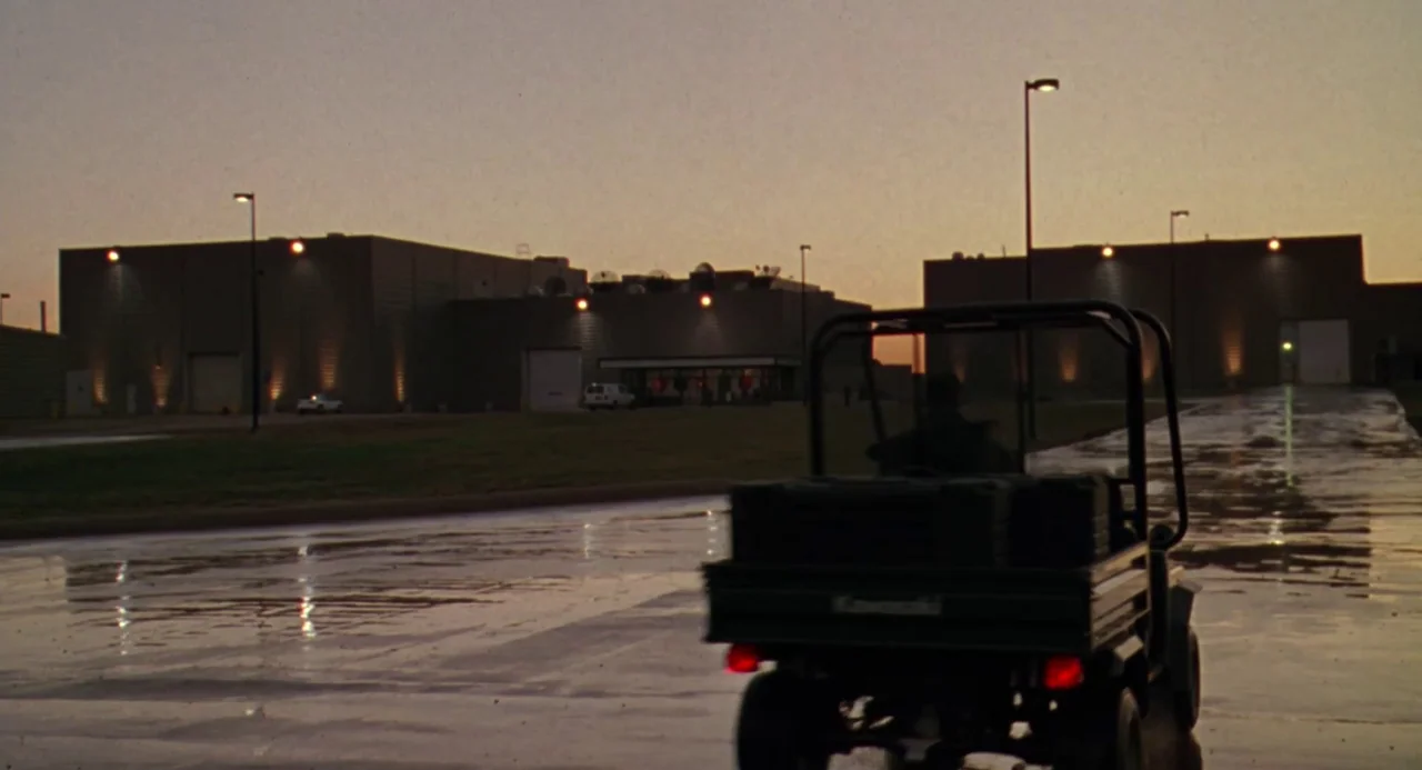 Universal Soldier: The Return (1999) movie still: wide — A vast industrial complex with large metallic buildings stands under a fading dusk sky. A…