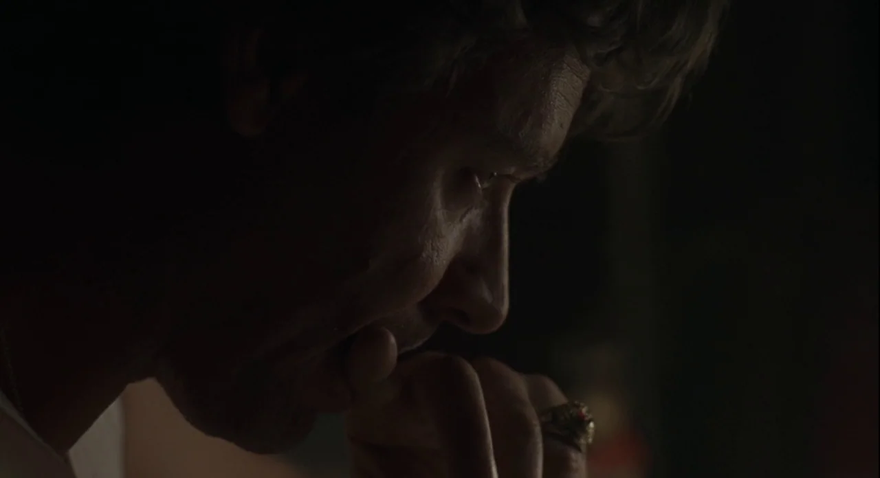 American Gangster (2007) movie still: closeup — A dark indoor space where the background is completely obscured by shadow. A man is shown in…