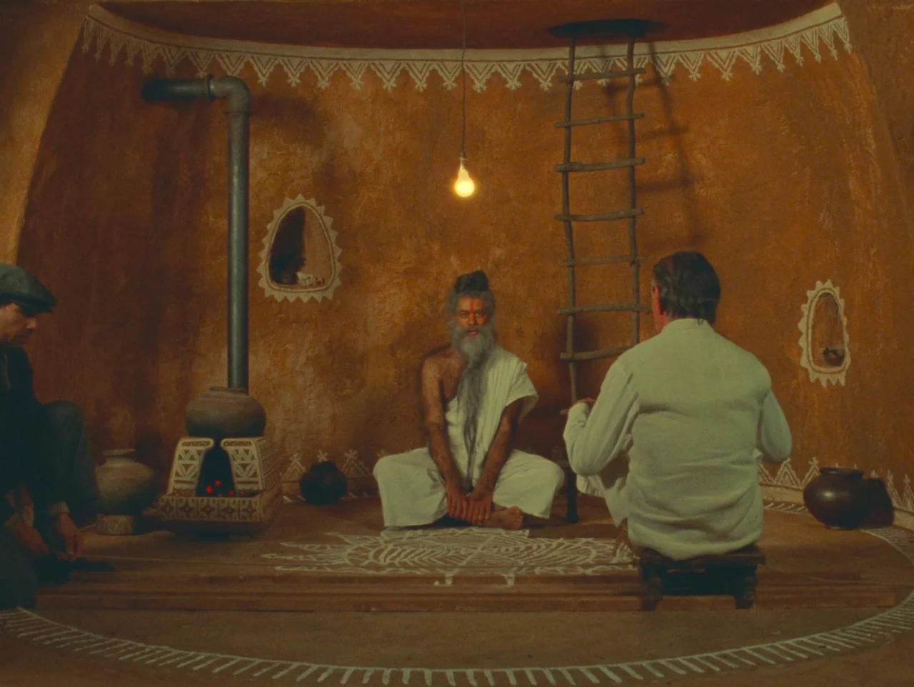 The Wonderful Story of Henry Sugar (2023) movie still: wide — A circular room with orange earthen walls decorated with white painted traditional…