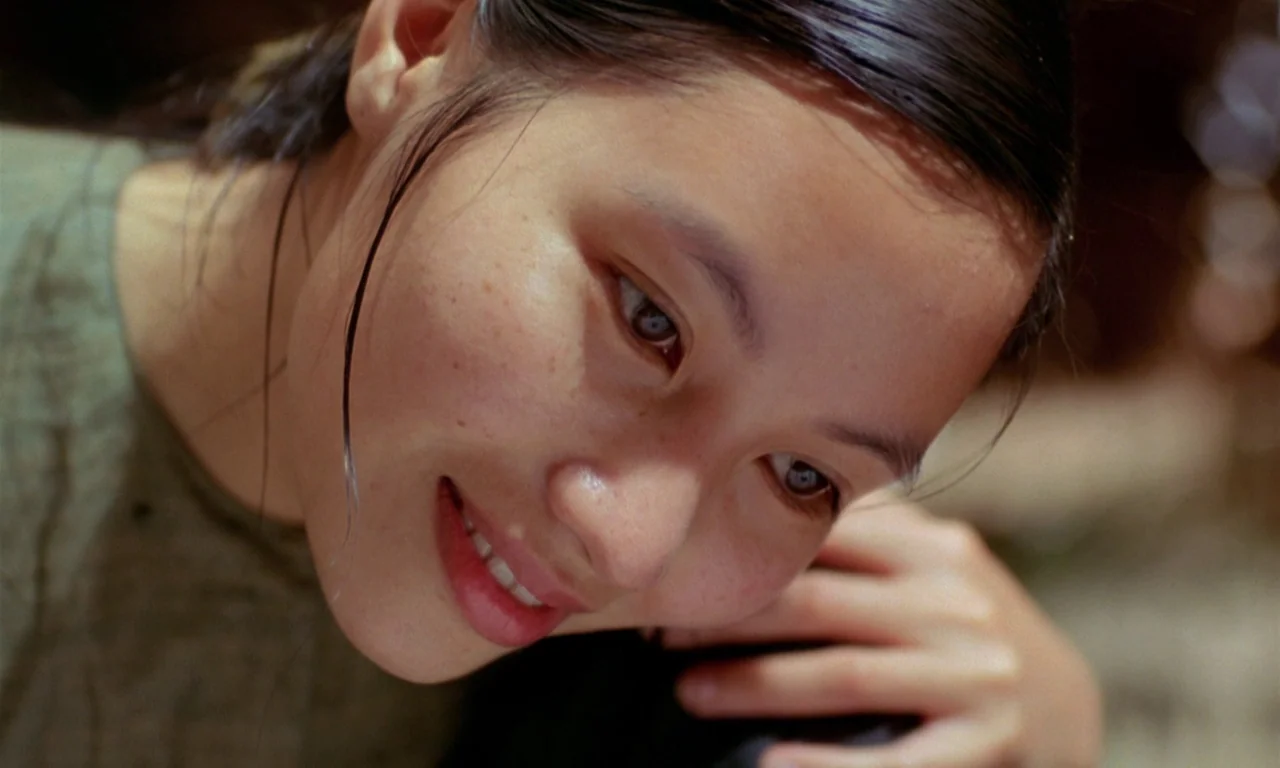 The Scent of Green Papaya (1993) movie still: closeup — A woman's face is shown in a close-up against a blurred natural outdoor background. She…